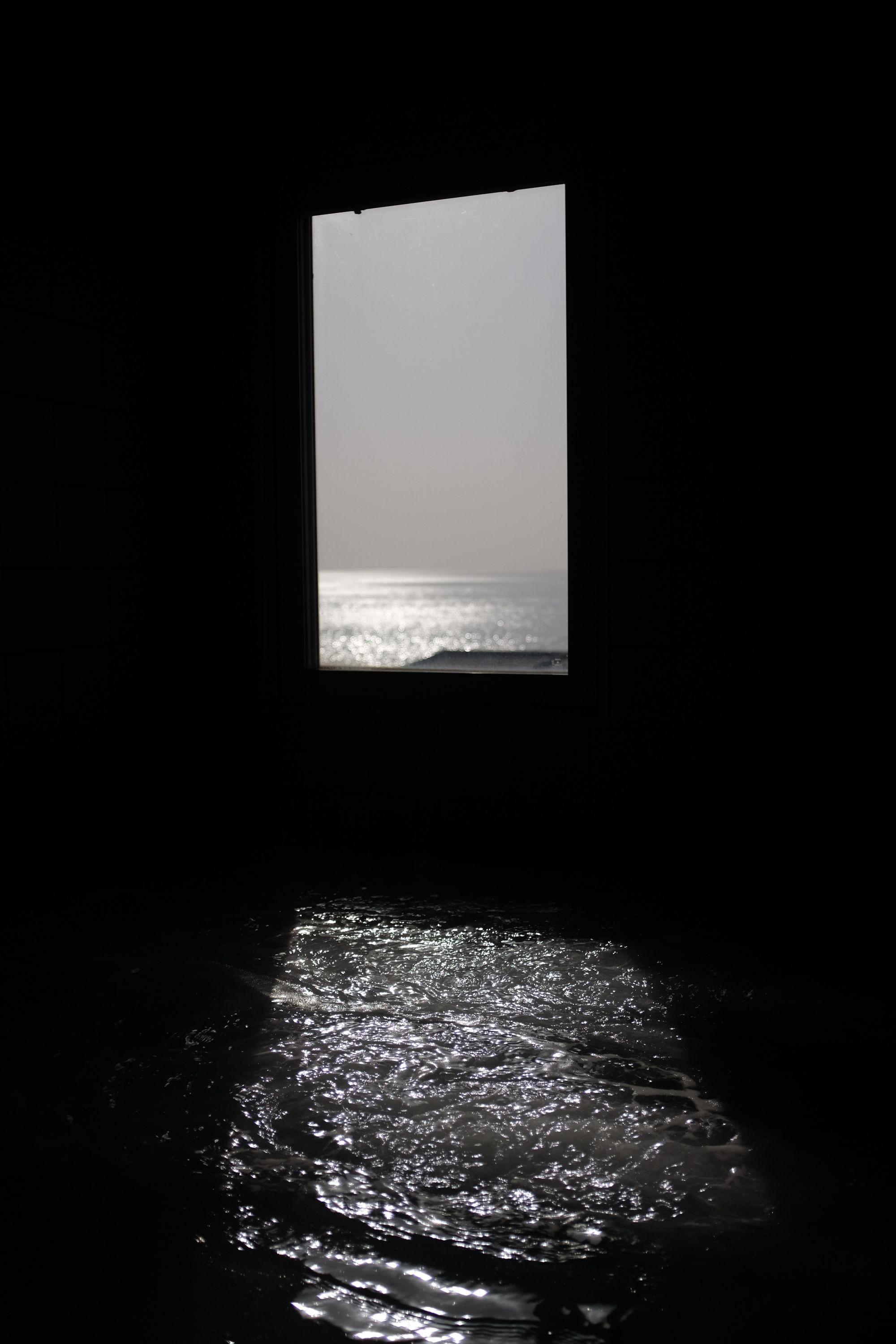 A view across the bathtub of a public bath and out a window shows the Inland Sea.