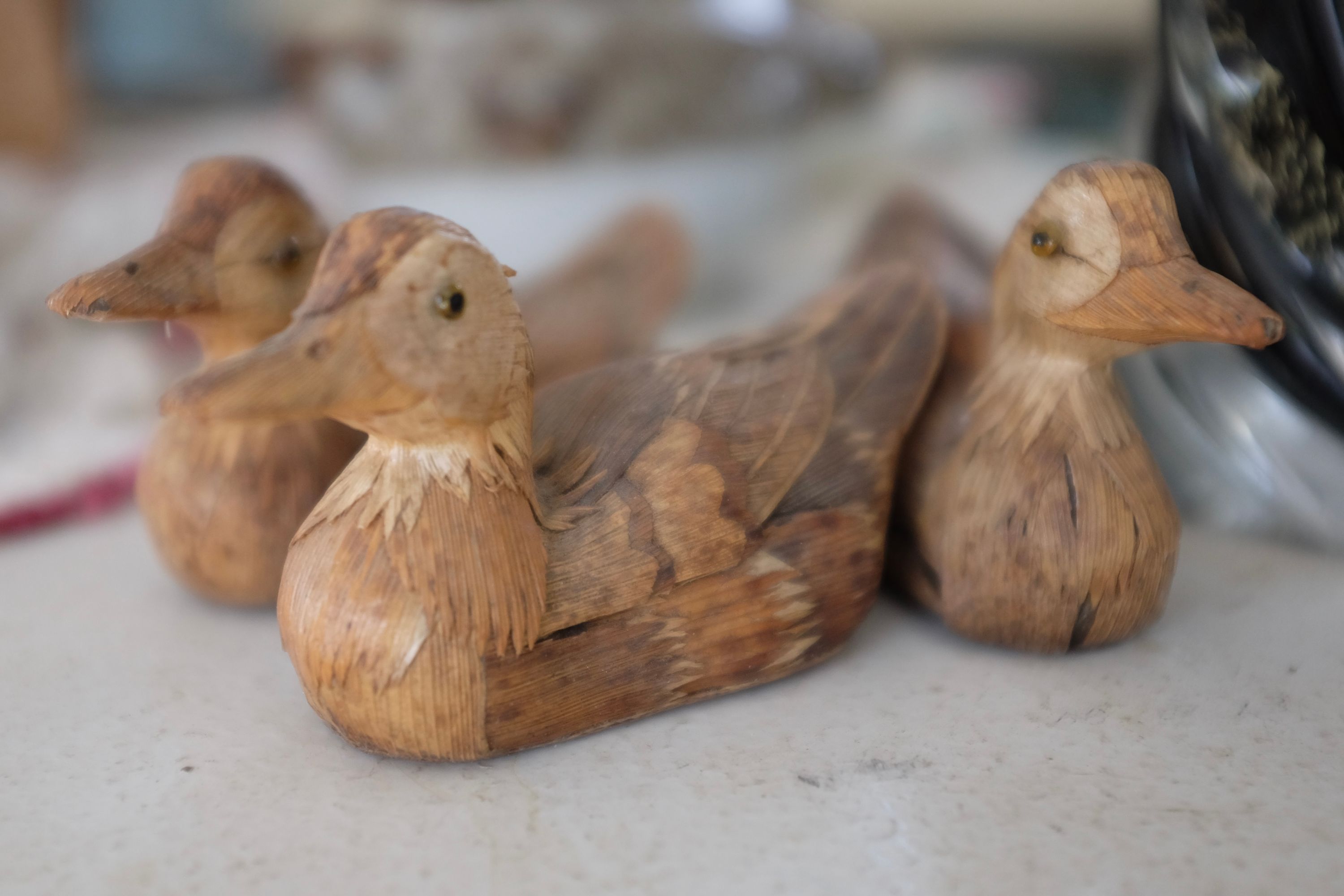 Three ducks made of tree bark on the shelf of a village shop.