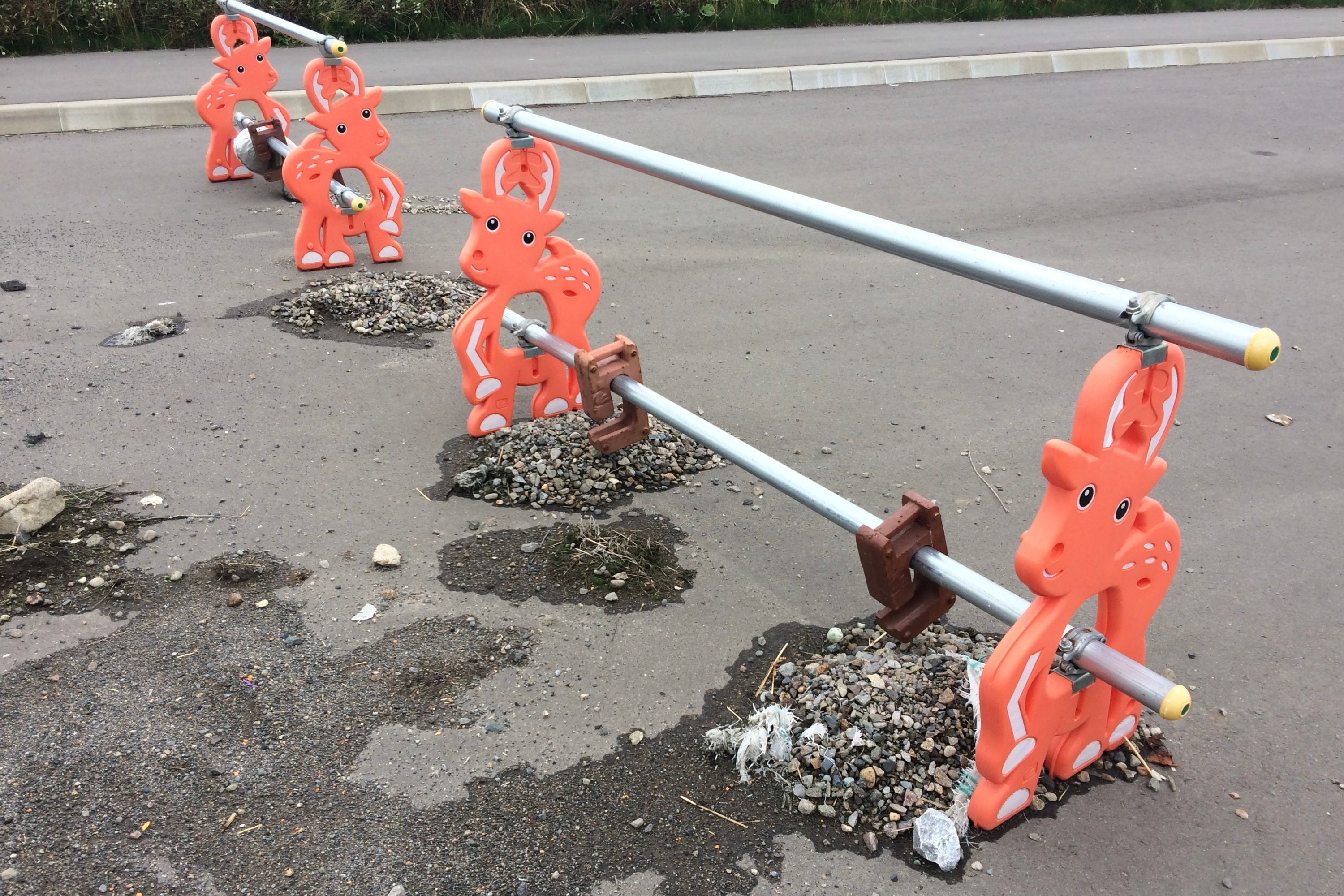 Four deer-shaped plastic bollard at a road repair site.