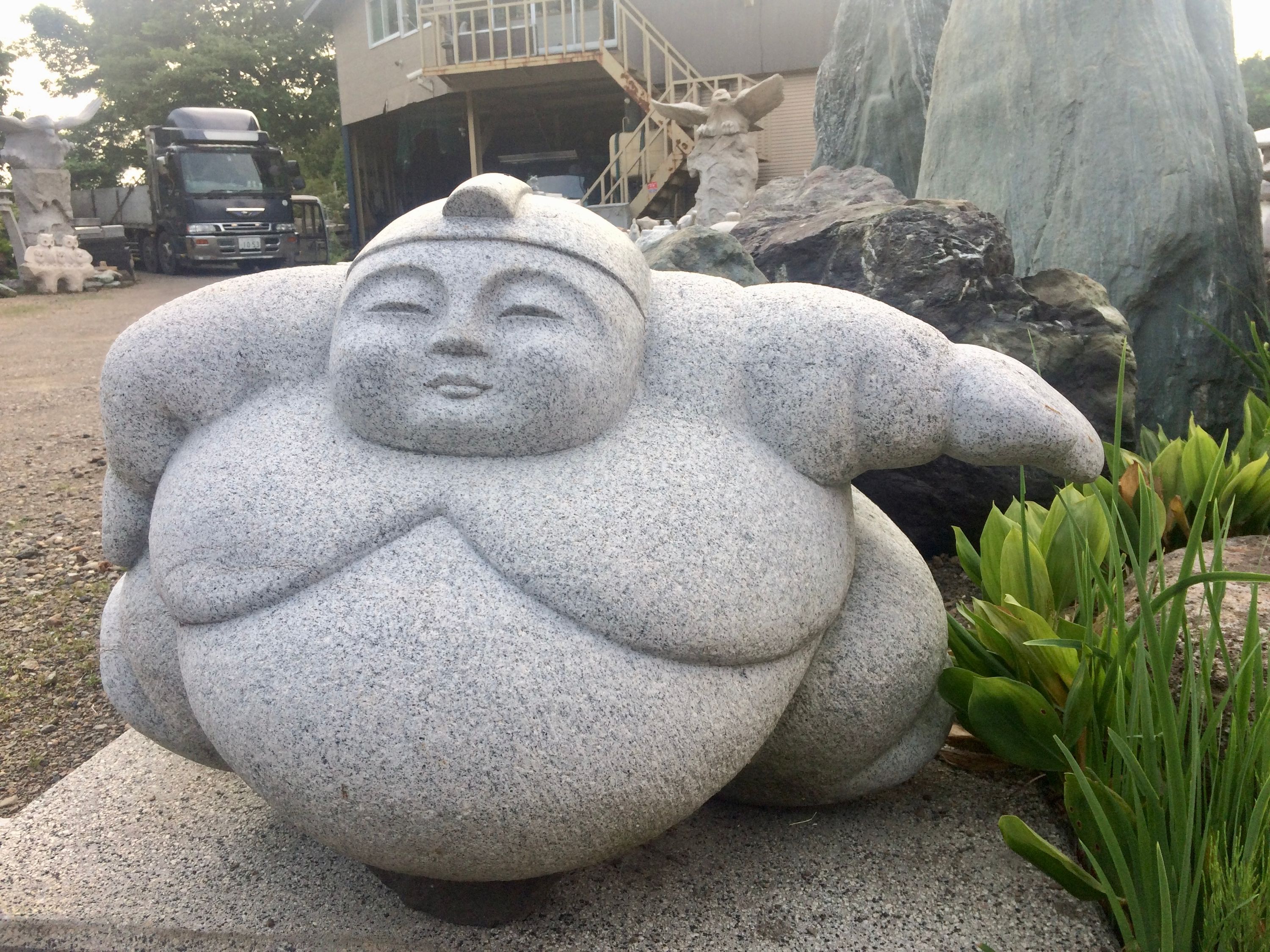 A simple statue of a very large sumo wrestler in a front yard.